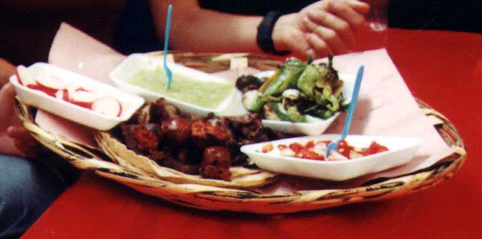 This is a BBQ plate with all of the trimmings.  Included with the meat are radishes, green salsa, grilled vegetables, and onions and tomatoes.
